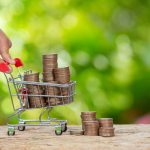 World Habitat Day,close up picture of  a hand pushing little cart which full of coins